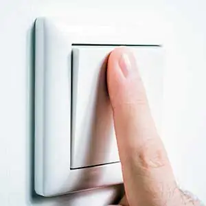 Schaltzyklen: Mann betätigt Lichtschalter mit Zeigefinge